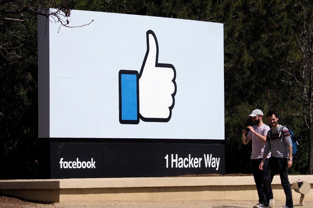 Dos hombres caminan junto a un icono de Facebook en Menlo Park, California, EE.UU.