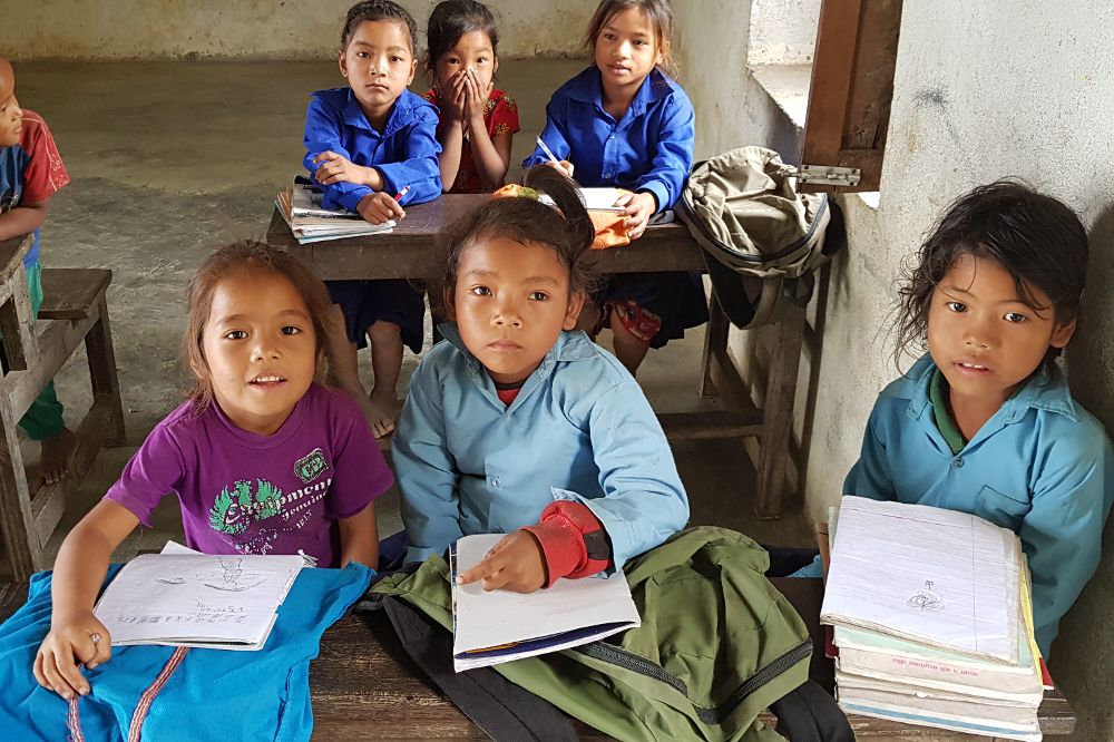 Niños nepalíes con sus cuadernos y otro material escolar en una escuela de Educanepal.