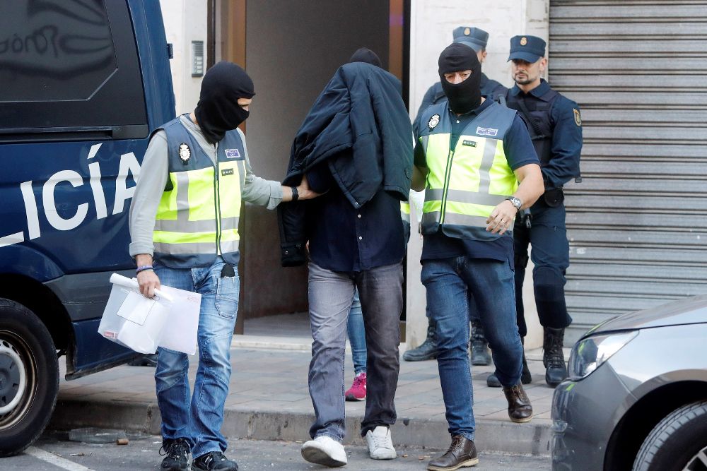 La Policía Nacional escolta al detenido en las localidad de Alaquàs (Valencia), sospechoso de difundir en redes sociales la doctrina de los grupos yihadistas Dáesh y Al Qaeda. 