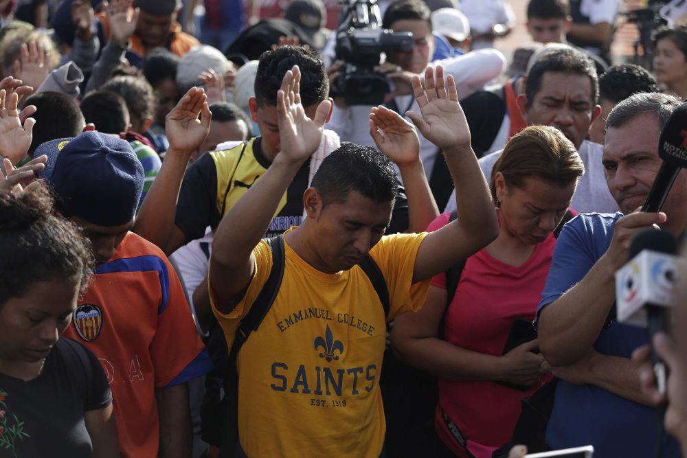 Migrantes salvadoreños rezan antes de iniciar su recorrido, el pasado domingo, desde la Plaza El Salvador del Mundo, en San Salvador.