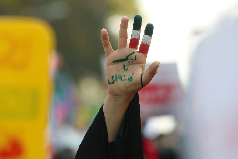 Una mujer iraní muestra su mano pintada con los colores nacionales.