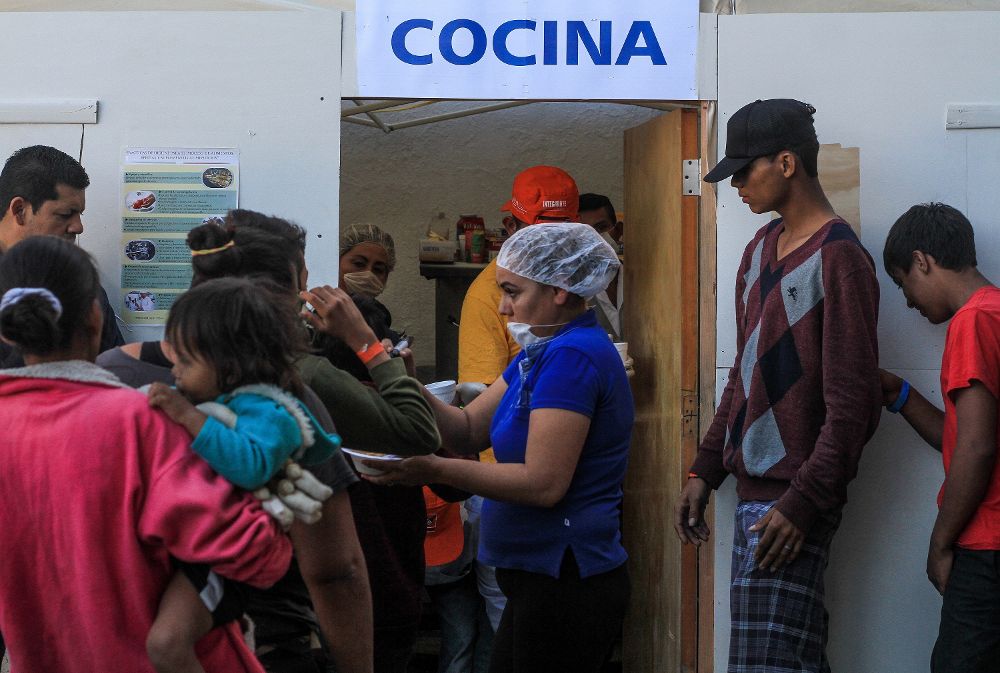 Integrantes de la caravana de migrantes centroamericanos reciben comida en el deportivo Benito Juárez, en la ciudad de Tijuana en el estado de Baja California (México). 