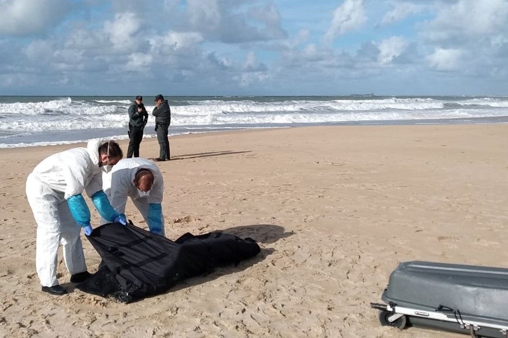 Los servicios funerarios recogen el cadáver de un inmigrante en la playa en Chiclana.