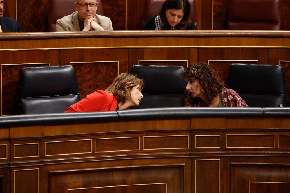 La ministra de Justicia, Dolores Delgado (a la izquierda), habla con la de Hacienda durante la sesión de control al Gobierno en el Congreso.