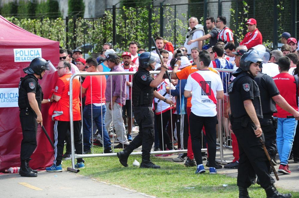 Integrantes de la policía argentina vigilan frente a aficionados de River Plate.