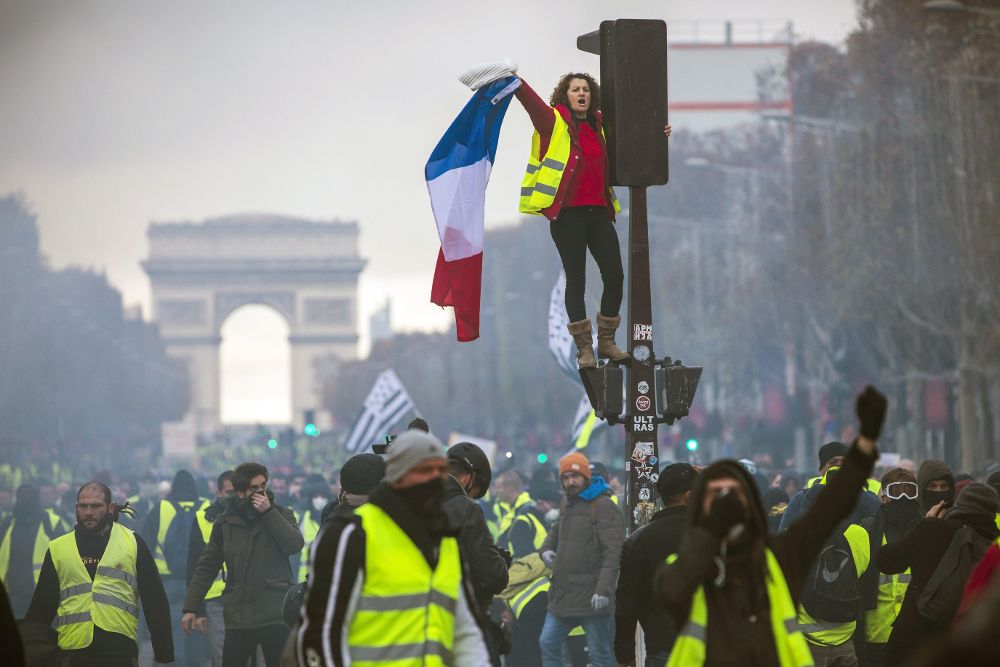 Una mujer grita consignas subida a un semáforo durante una protesta en los Campos Elíseos en París (Francia) el 24 de noviembre de 2018.