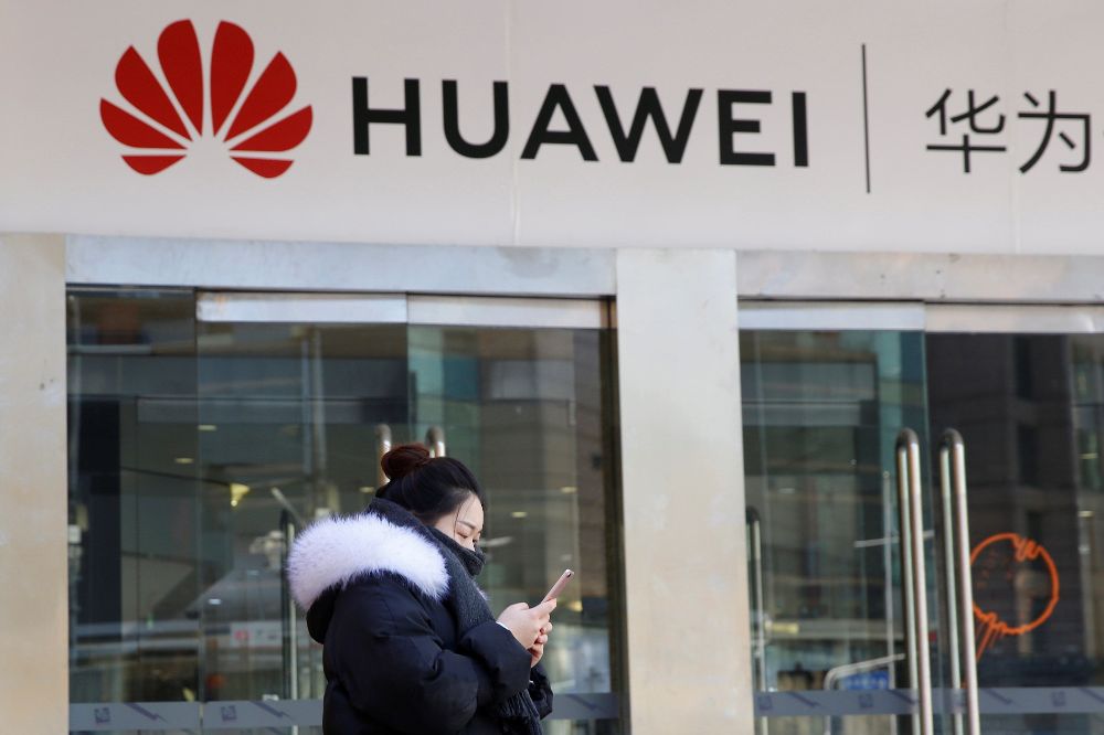 Una joven utiliza su teléfono móvil ante una tienda dela firma china Huawei en Pekín, China.