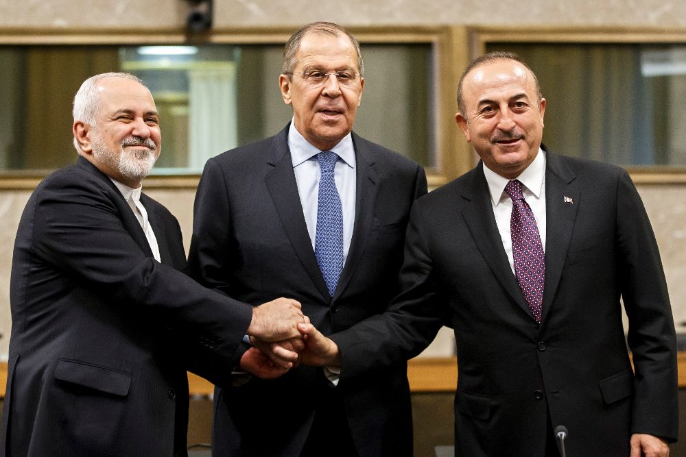 (De izq a der) el ministro de Exteriores iraní, Mohammad Javad Zarif; su homólogo ruso, Serguéi Lavrov; y su homólogo turco, Mevlut Cavusoglu, se estrechan la mano tras su reunión en la sede europea de la ONU en Ginebra (Suiza), hoy, 18 de diciembre de 2018. 