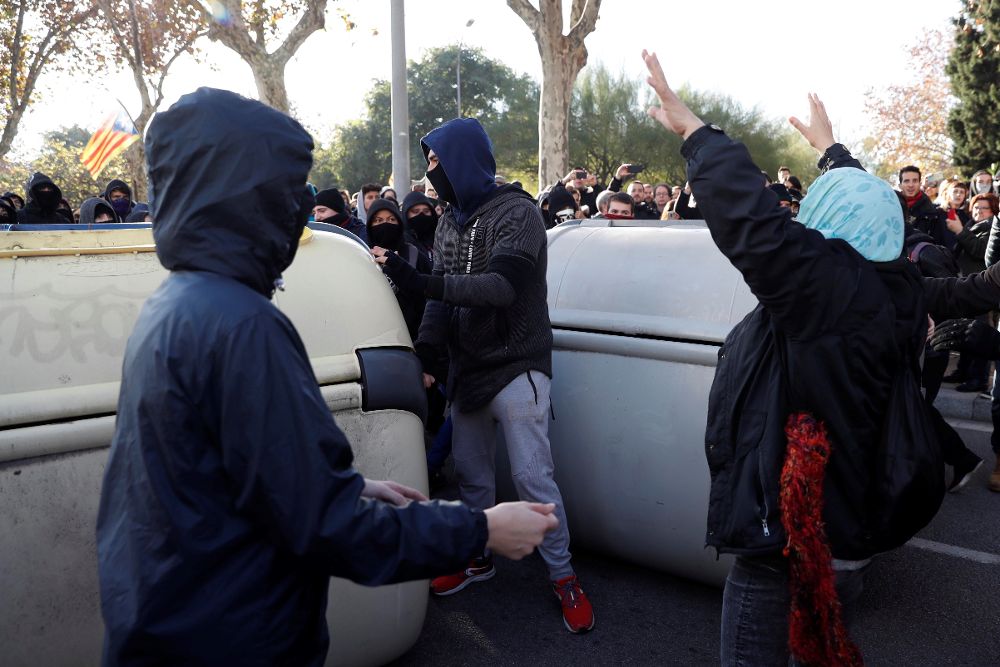 Manifestantes independentistas encapuchados vuelcan contenedores en las inmediaciones de la Llotja de Mar de Barcelona.