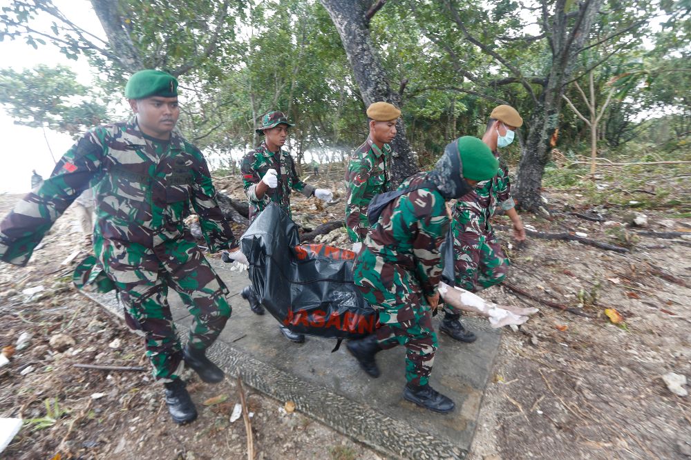 Soldados de los equipos de rescate transportan el cuerpo de una víctima del tsunami.