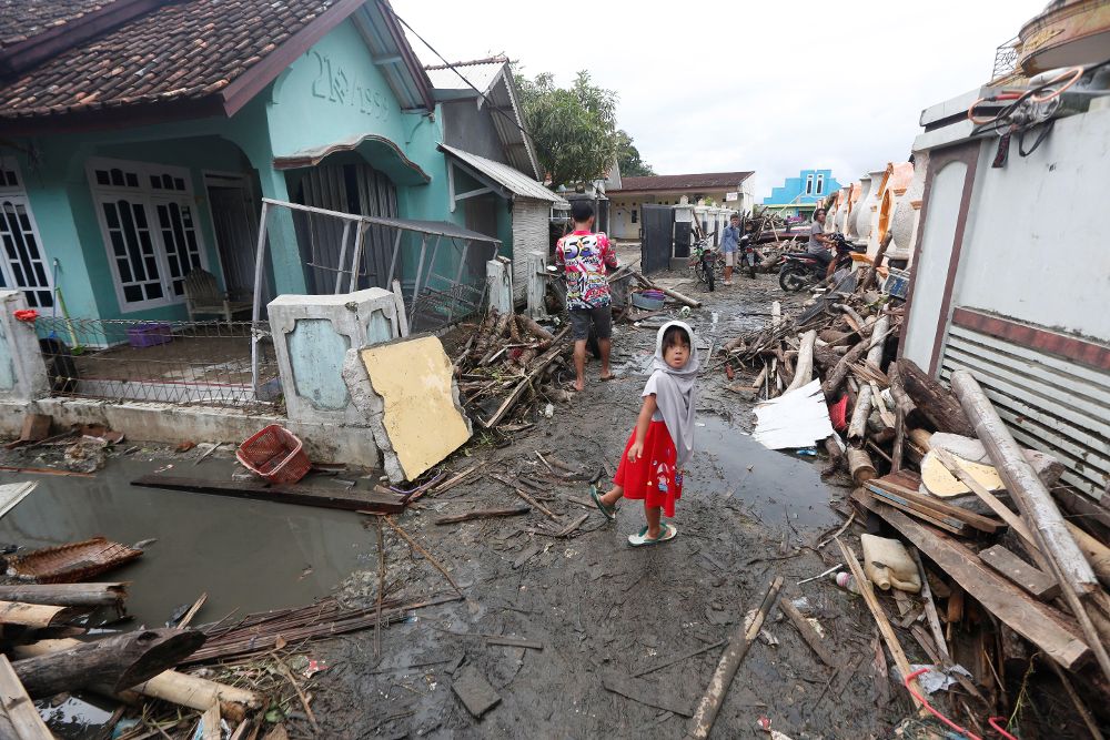 Los residentes locales caminan entre los escombros en un área devastada por el tsunami que golpeó el estrecho de Sunda en Sumur, Banten, Indonesia.