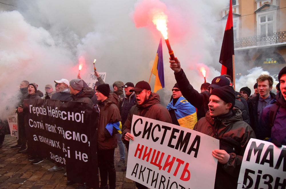 Activistas y nacionalistas ucranianos encienden bengalas y sostienen pancartas durante una protesta en la ciudad de Lviv, el 21 de diciembre.