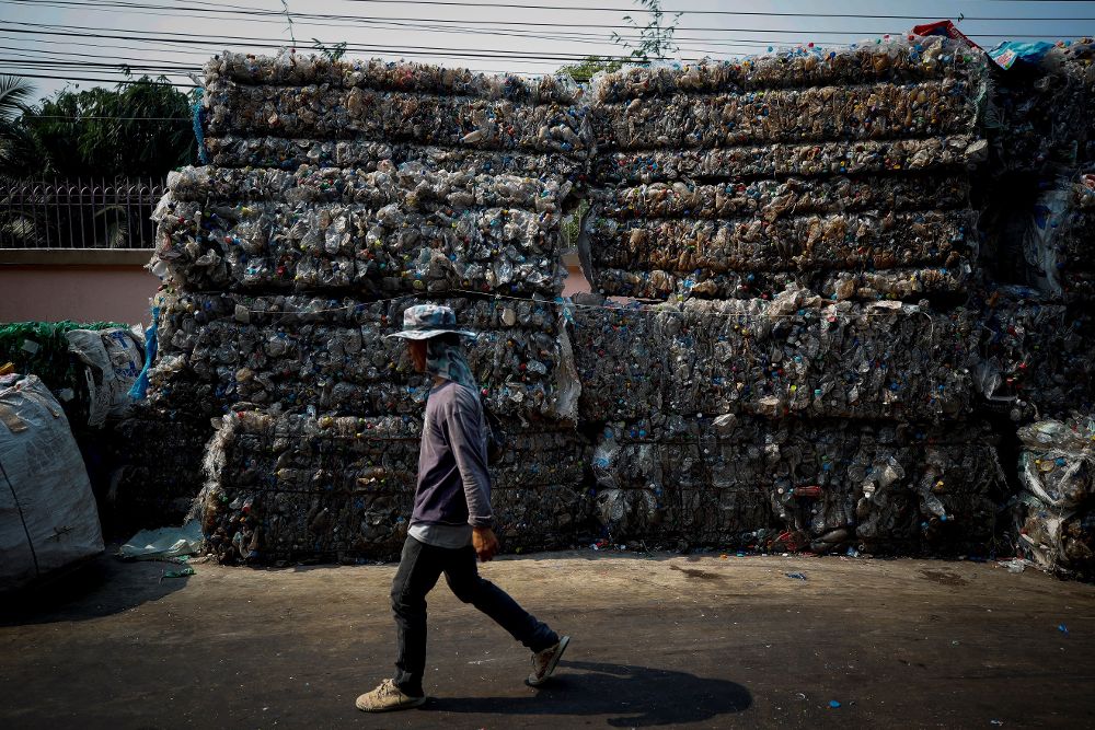 Un trabajador camina junto a pilas prensadas de botellas de plástico en una planta de reciclaje de Samut Sakhon, afueras de Bangkok.