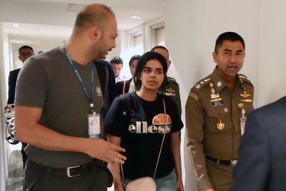 La joven saudí Rahaf Mohammed Al-Qunun conversa con el jefe de la policía de inmigración de Tailandia, Surachet Hakparn (d), y un trabajador de ACNUR (i) antes de abandonar el aeropuerto Suvarnabhumi en Tailandia.