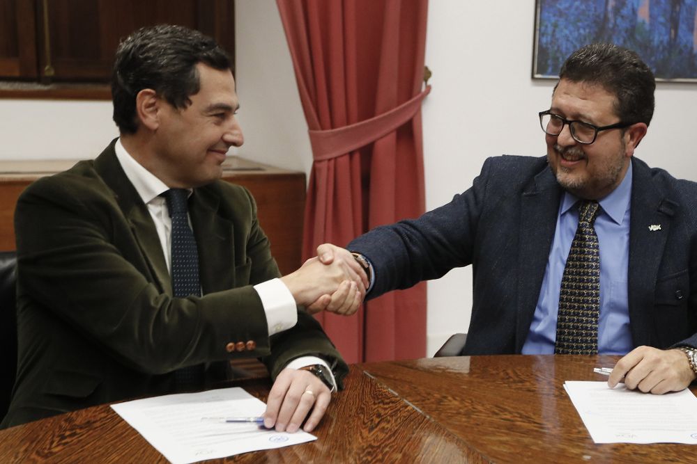 Juanma Moreno (i) estrecha la mano con el líder andaluz de Vox, Francisco Serrano.