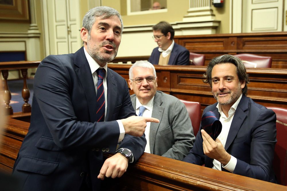 El presidente del Gobierno de Canarias, Fernando Clavijo (i), de CC, bromea, antes de comenzar la sesión plenaria del Parlamento regional, con el diputado socialista Gustavo Matos (d).