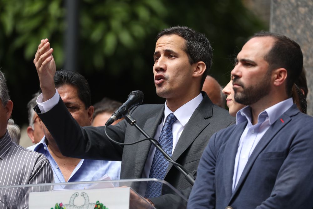 Juan Guaidó (C) habla este viernes durante su primera aparición pública desde que se adjudicó las competencias del Ejecutivo ante miles de personas, en una plaza en el este de Caracas.