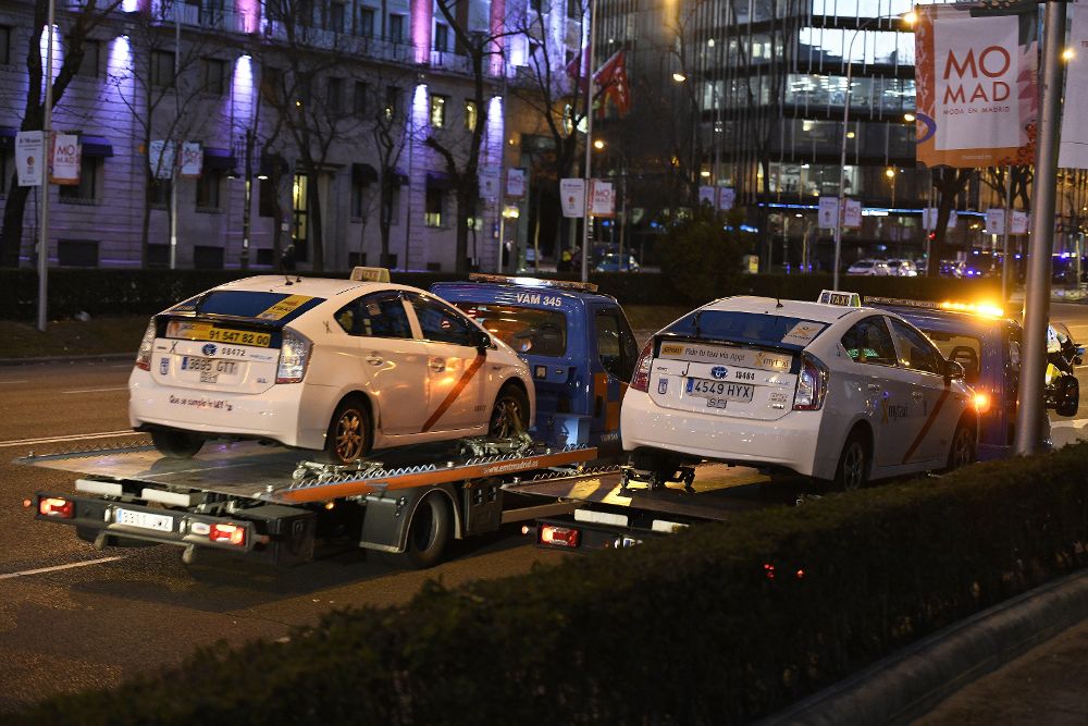 Dos grúas municipales retiran taxis del Paseo de la Castellana de Madrid.