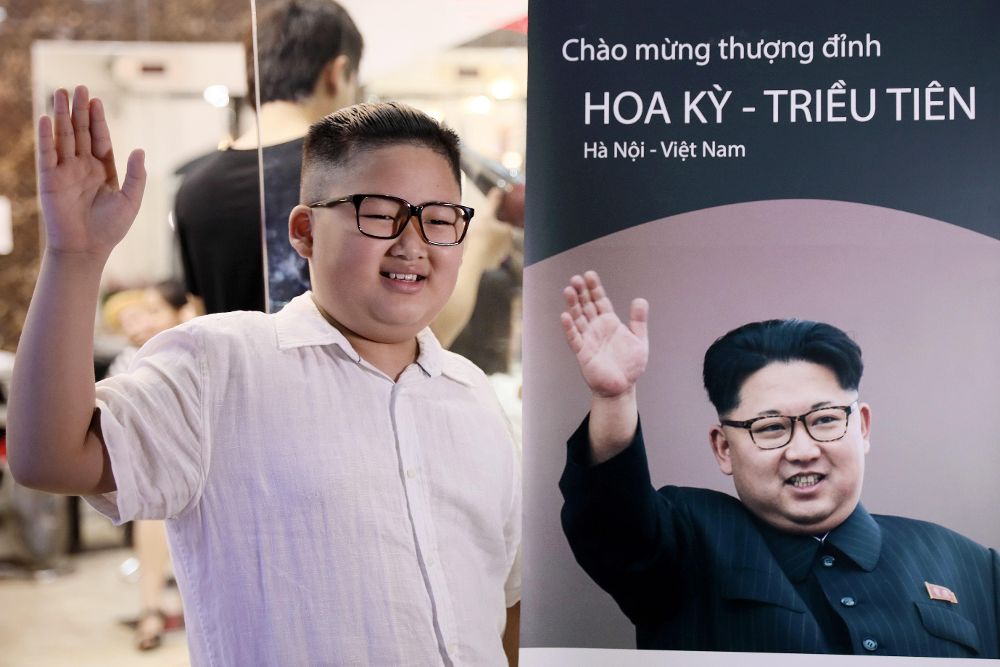 Un niño posa con un peinado similar al de Kim Jong-un junto a un cartel en el que aparece el líder norcoreano.