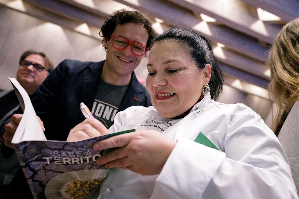 La cocinera Bárbara González firma un ejemplar del libro "Sabe a territorio", presentado este lunes durante el "Encuentro con mujeres de la gastronomía".