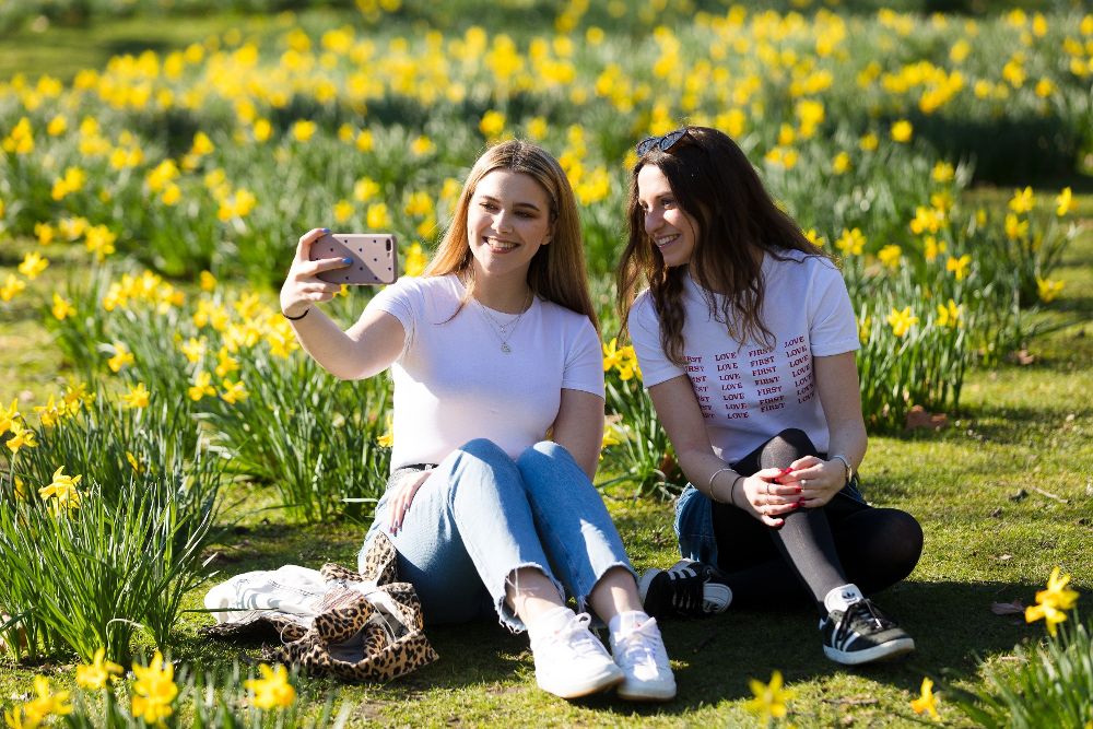 Dos mujeres se fotografían en un prado de narcisos durante una mañana primaveral en el centro de Londres.