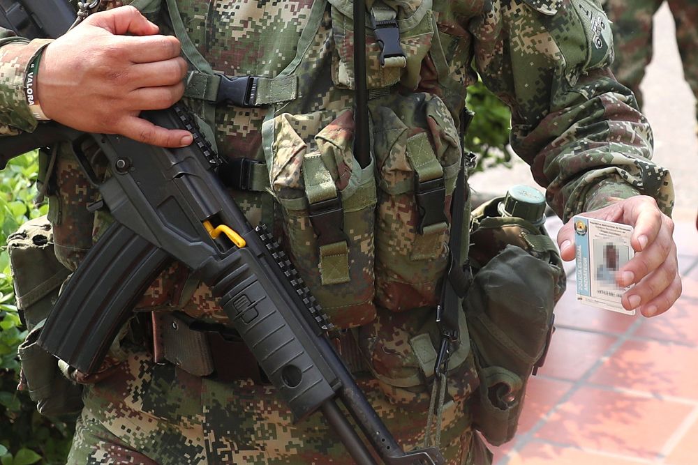 Fotografía modificada digitalmente en la que se observa a un militar del Ejército de Colombia mostrando el carné de un policía venezolano que desertó este miércoles, en Cúcuta (Colombia).