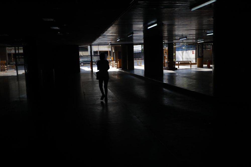 Una persona camina por un parqueadero sin luz este sábado, en Caracas (Venezuela).