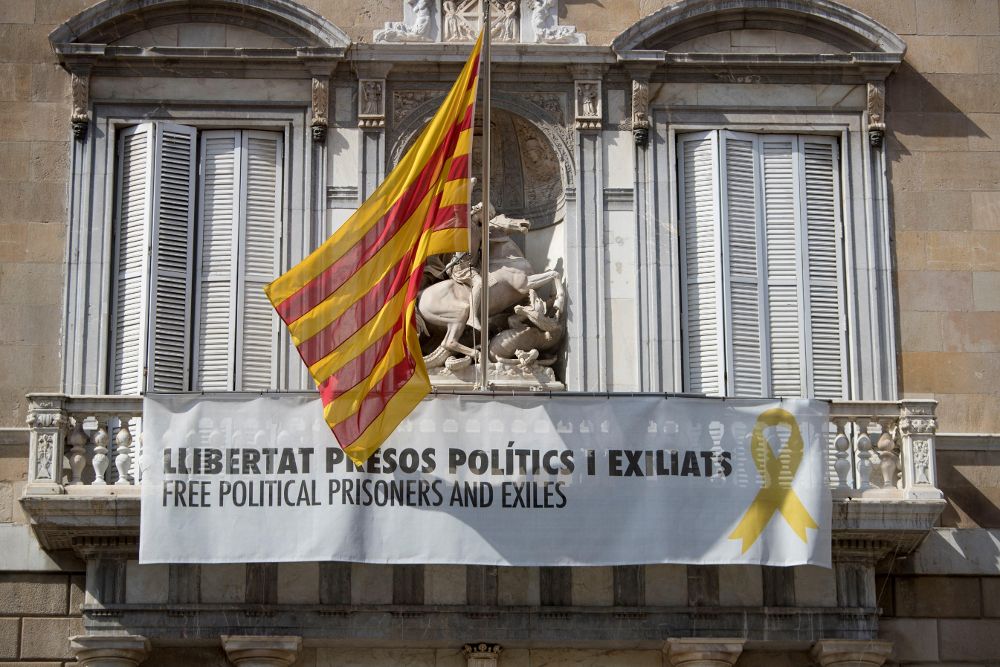 Vista de la fachada del Palau de la Generalitat, de donde cuelga, junto a la bandera catalana, un cartel y un lazo amarillo reivindicando la libertad de los políticos encarcelados.