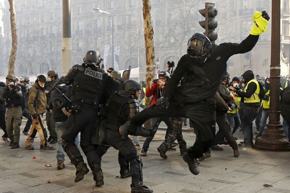 Un "chalecop amarillo" se lanza contra un policía durante las protestas de hoy en París.