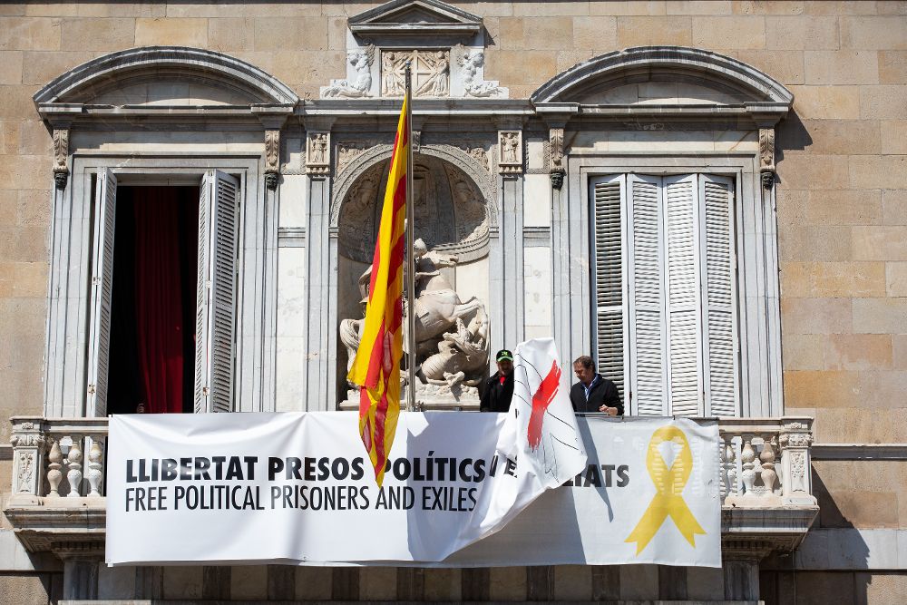 Colocación de la pancarta blanca que tapaba la anterior con el lazo amarillo en el balcón del palacio de la Generalitat.